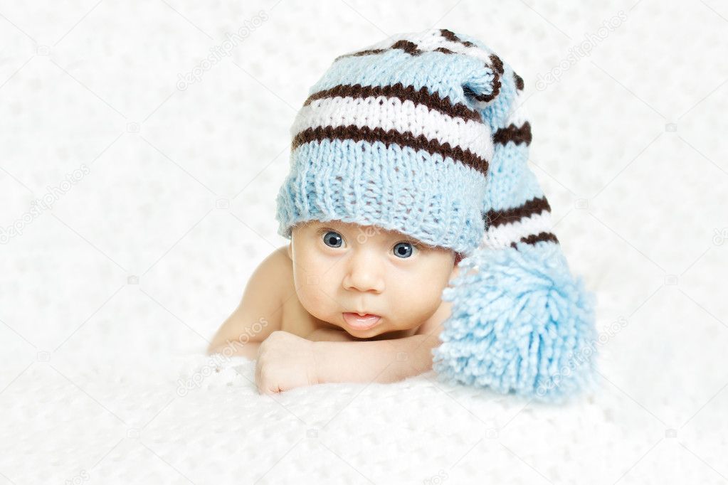 Newborn baby closeup portrait in blue woolen hat over white soft
