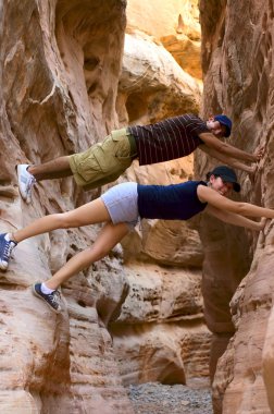 Two teenage hikers taking a break and having fun inside a canyon in Nevada clipart