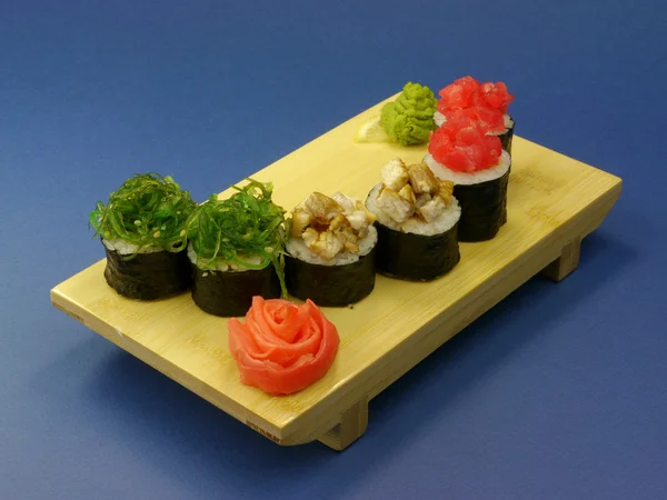 Deliciosos rolos de sushi em placa de madeira — Fotografia de Stock