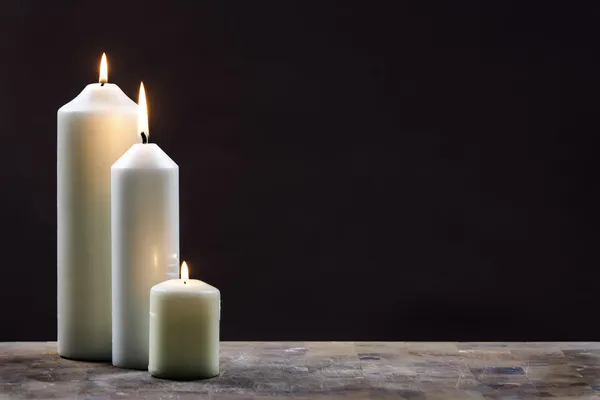 Três velas contra fundo escuro — Fotografia de Stock