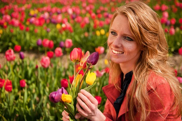 Holländska blond flicka i fält med tulpaner — Stockfoto