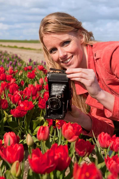 Menina loira holandesa com câmera de foto velha no campo com tulipas — Fotografia de Stock