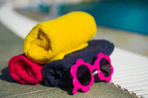 Towels and sunglasses at swimming pool — Stock Photo, Image