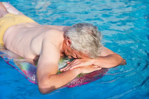 空気マットレスの上浮かんでいる高齢者の男 — ストック写真