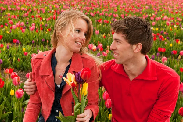 Gelukkige jonge paar in Nederlandse bloembollenvelden — Stockfoto