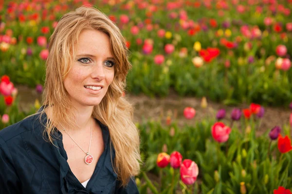 Holländska blond flicka i fält med tulpaner — Stockfoto