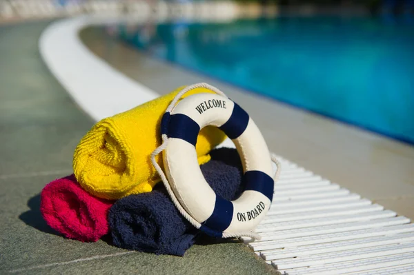 Towels and life buoy at swimming pool — Stock Photo, Image