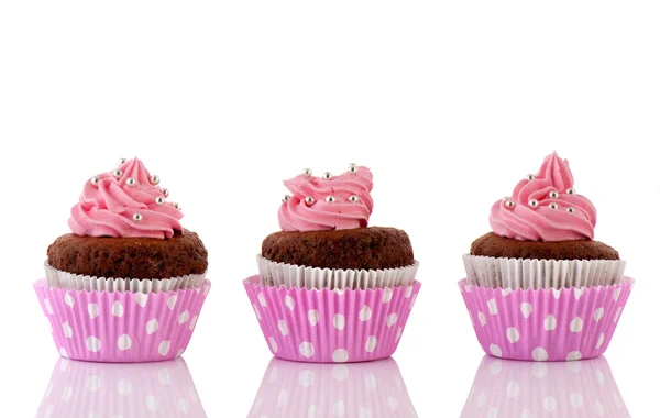 Drie chocolade cupcakes met roze boter suikerglazuur Stockfoto