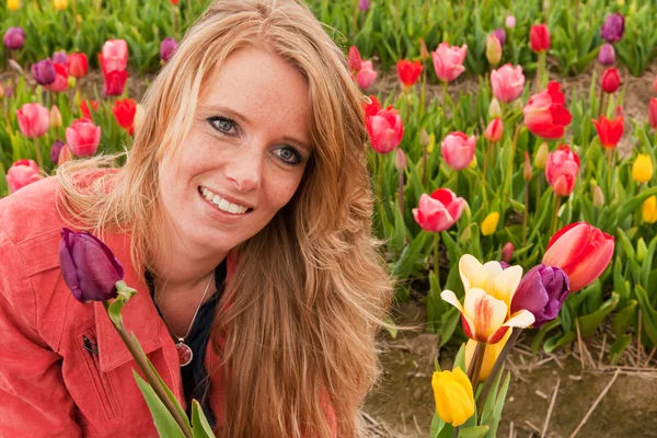 Holländska blond flicka plockar blommor i tulpaner fält — Stockfoto