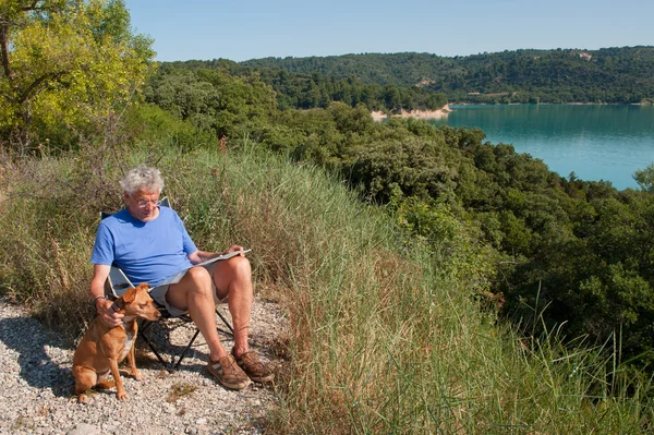 Ο άνθρωπος με το σκυλί κάθεται στο γαλλικό τοπίο — Φωτογραφία Αρχείου