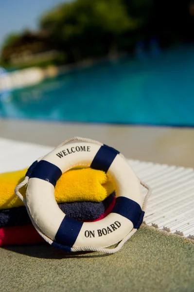 Toalhas e bóia de vida perto da piscina — Fotografia de Stock