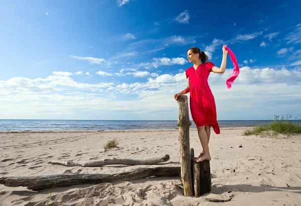 在海滩上穿红裙子的女孩. — 图库照片