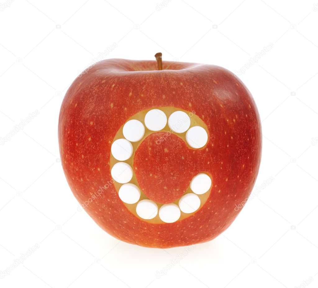Red apple with vitamin c pills over white background - concept