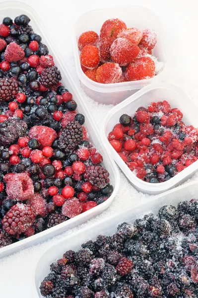 Пластиковые контейнеры из замороженных смешанных ягод в снегу - красная смородина, клюква — стоковое фото