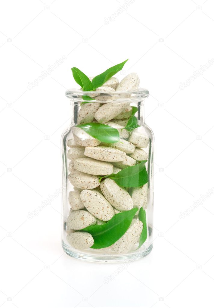Herbal supplement pills and fresh leaves in glass – alternative medicine c