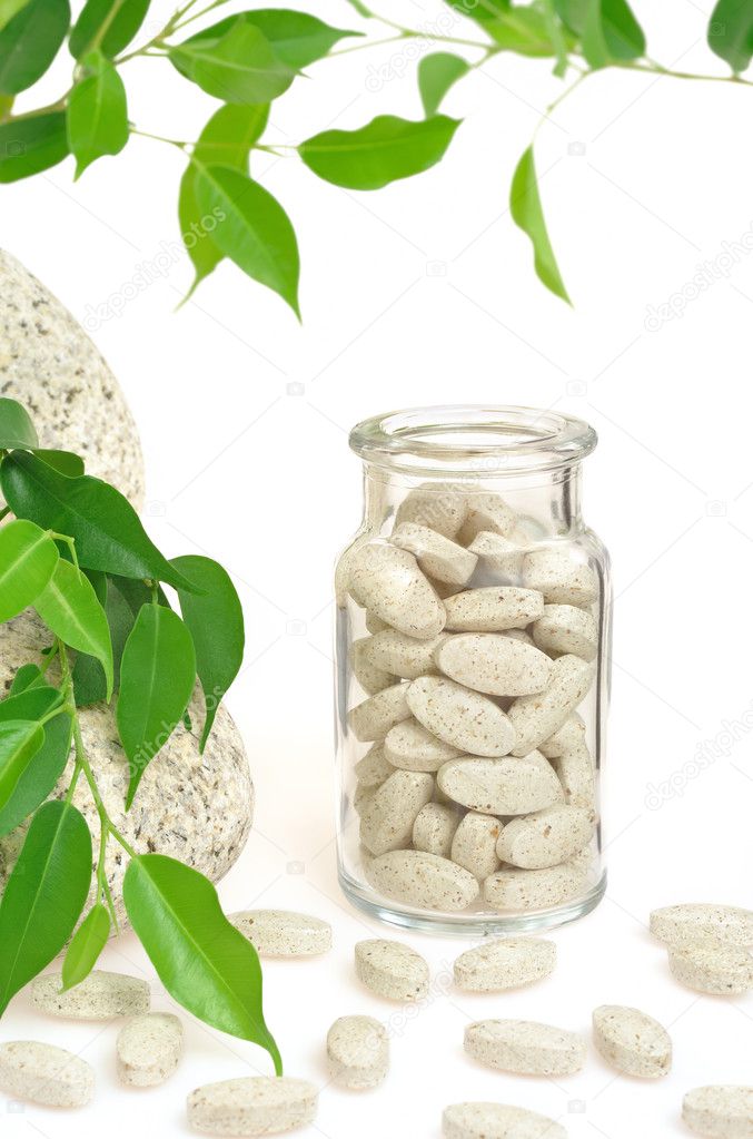 Herbal supplement pills and fresh leaves – alternative medicine still life