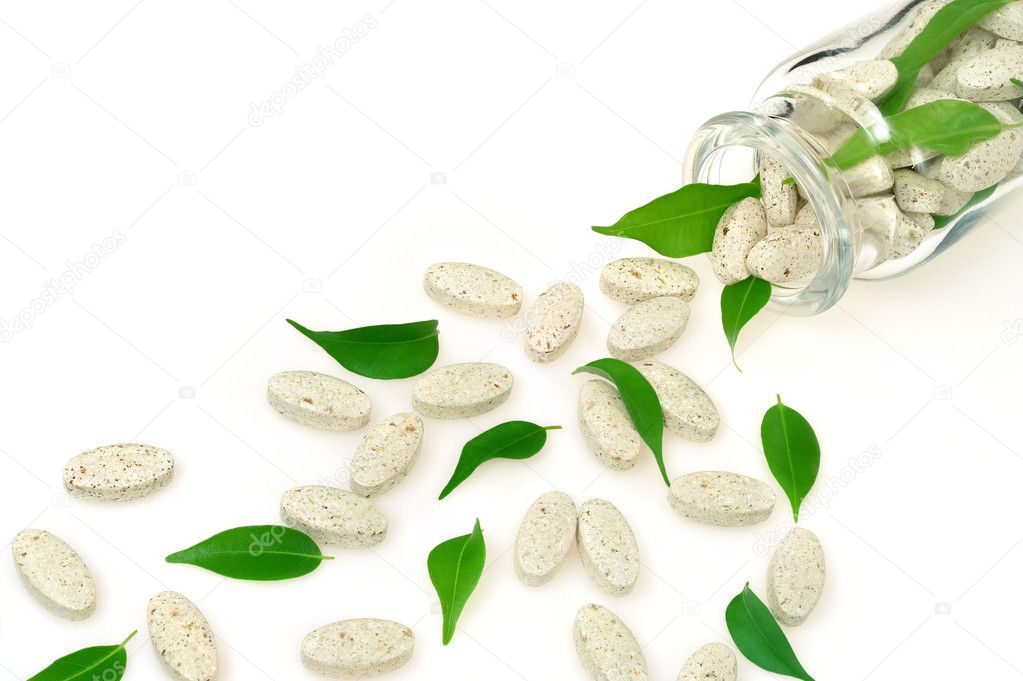 Herbal supplement pills and fresh leaves spilling out of bottle – alternat