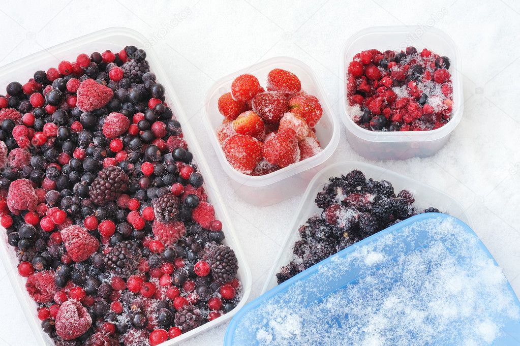 Plastic containers of frozen mixed berries in snow - red currant, cranberry