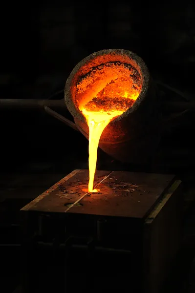 Gießerei - geschmolzenes Metall aus Schöpfkelle in Form gegossen - Wachsabguss lizenzfreie Stockbilder