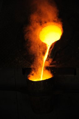 Foundry - molten metal poured from ladle for casting clipart