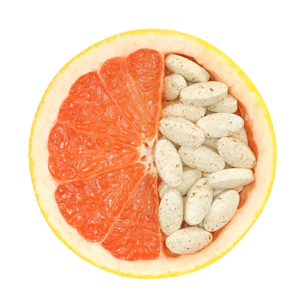Закрыть красный грейпфрут и таблетки изолированы - концепция витаминов — стоковое фото