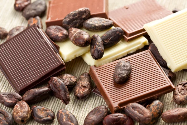 Various chocolate bars with cocoa beans — Stock Photo, Image