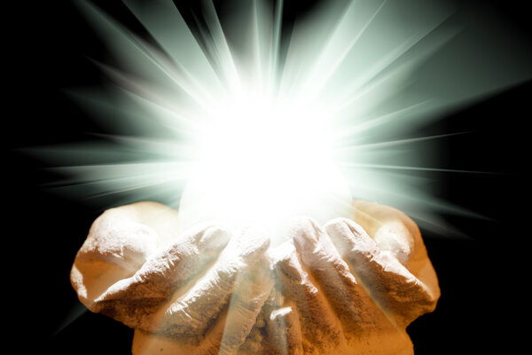 Spiritual light in cupped hands on a black background