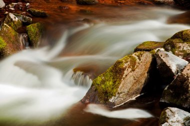 Flowing river blurred through rocks clipart