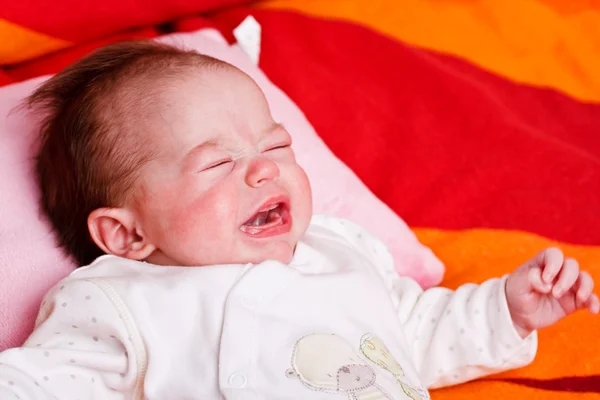 Baby girl lying on a soft blanket and crying — Stock Photo, Image