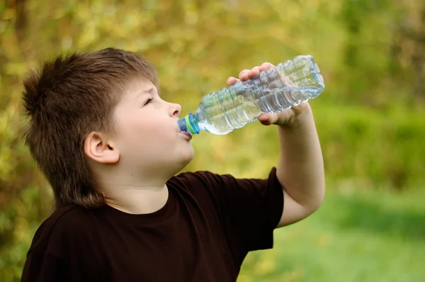 En pojke med en flaska vatten i naturen — Stockfoto
