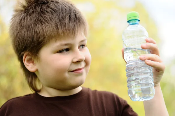 En pojke med en flaska vatten i naturen — Stockfoto