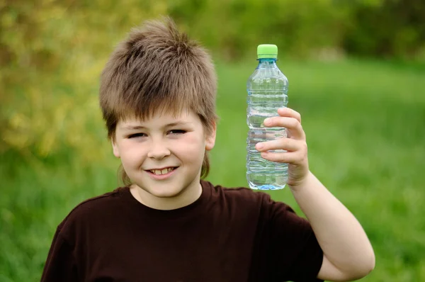 Un garçon avec une bouteille d'eau dans la nature — Photo
