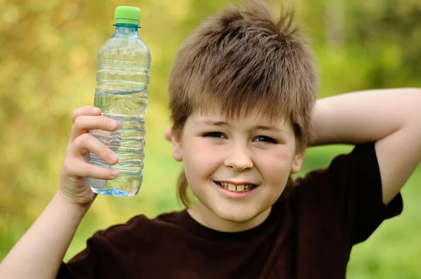 Un niño con una botella de agua en la naturaleza —  Fotos de Stock