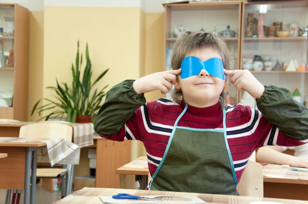 De jongen maakt een maskerade masker in de klas op school — Stockfoto