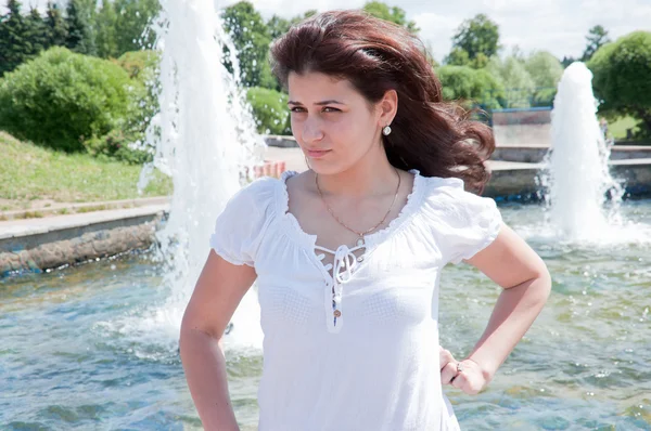 stock image Young dark-haired girl at the fountain in the park