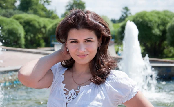 stock image Young dark-haired girl at the fountain in the park