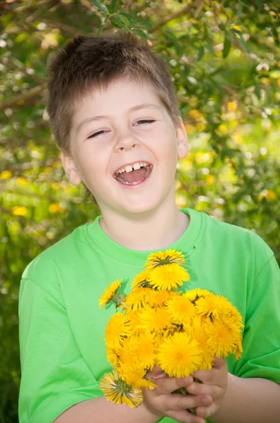 Laughing boy with a bouquet of dandelions — Stock Photo, Image