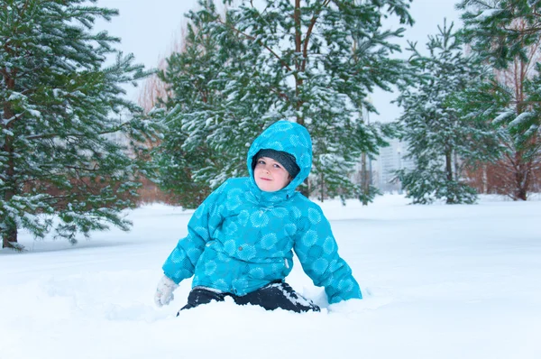 Мальчик в синей куртке, гуляющий в зимнем парке — стоковое фото