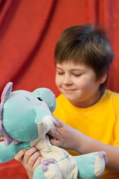 Um menino com um dragão de brinquedo macio - um símbolo do ano novo — Fotografia de Stock