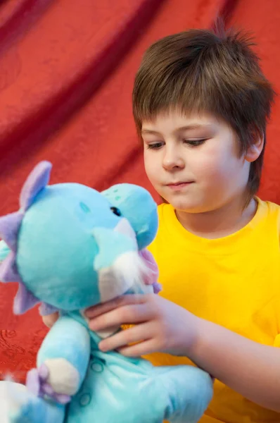 Un ragazzo con un drago giocattolo morbido - un simbolo del nuovo anno — Foto Stock