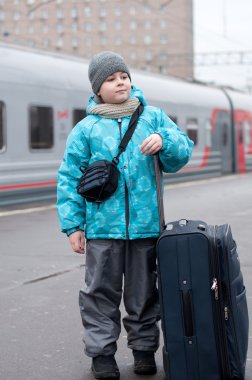 bir çocuk bir trenin yanında seyahat çantası