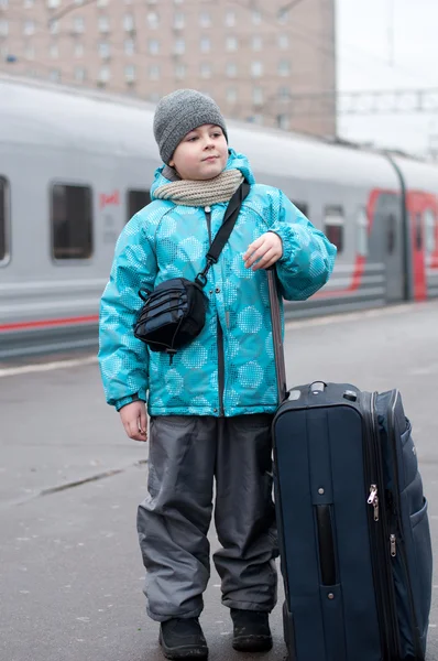 A boy with a travel bag near a train — Stock Photo, Image