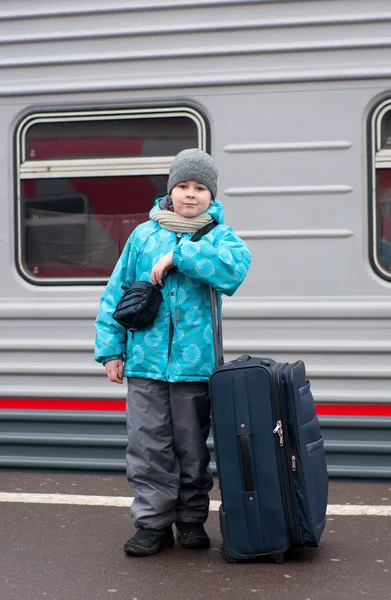 Un chico con una bolsa de viaje cerca de un tren — Foto de Stock