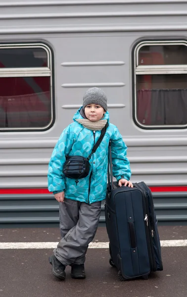 A boy with a travel bag near a train — Stock Photo, Image
