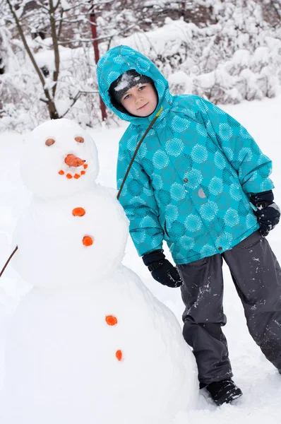 En pojke och en snögubbe - en vintersemester — Stockfoto
