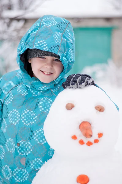 En pojke och en snögubbe - en vintersemester — Stockfoto