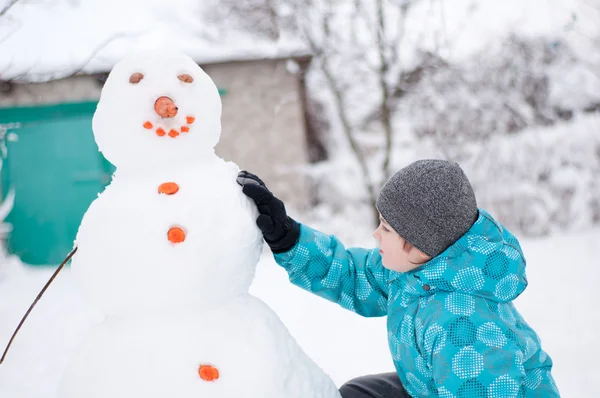 En pojke och en snögubbe - en vintersemester — Stockfoto