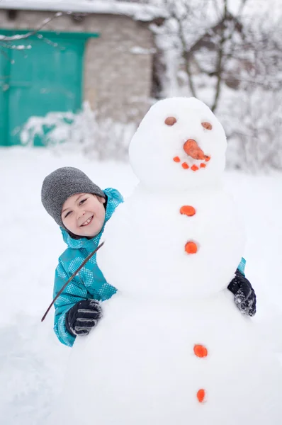 Мальчик и снеговик - зимний отдых — стоковое фото