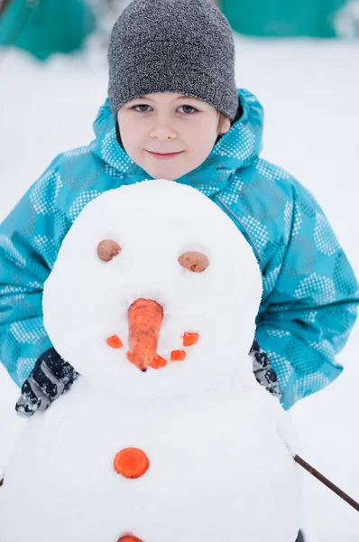 Chlapec a sněhulák - zimní dovolená — Stock fotografie