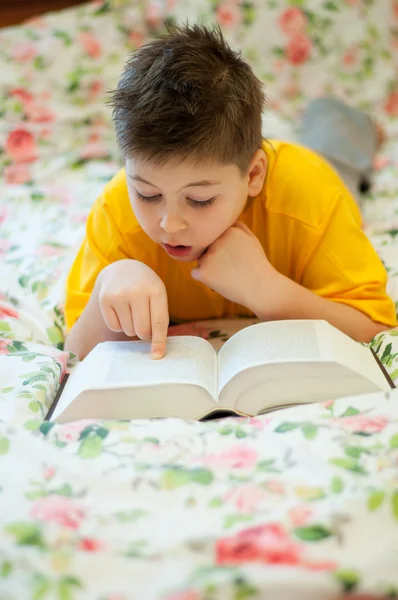 A boy reads a book in bed — Stock Photo, Image